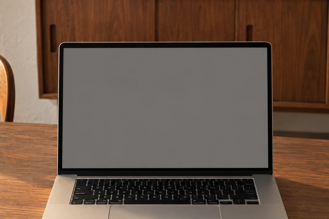 A laptop on a walnut mid-century table in late afternoon light