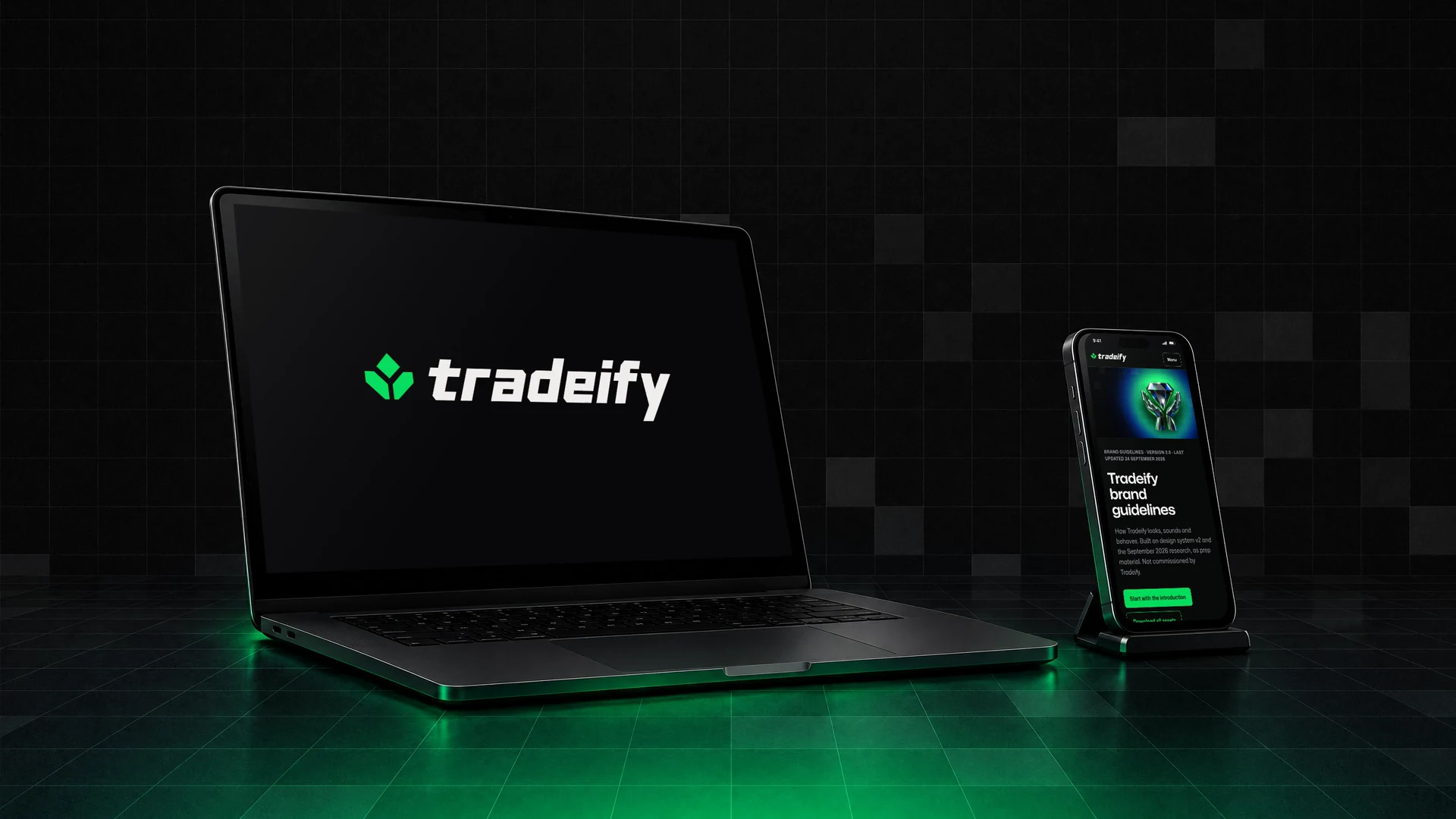 The proposed Tradeify lockup on a laptop, the guidelines site on a phone beside it, in a dark room with a lit grid floor